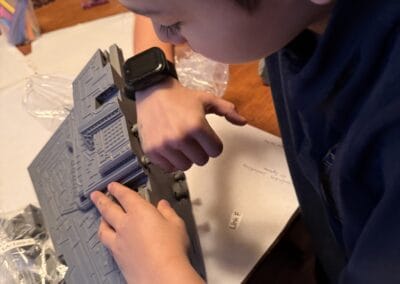Child assembling LEGO Star Wars Millennium Falcon with focus and concentration.