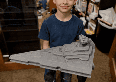 Boy holding detailed Star Wars spaceship model in room.