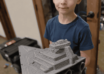 Boy holding detailed Star Wars LEGO spaceship model in room.